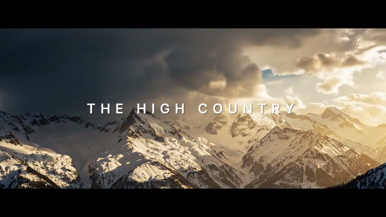 Storm clouds over snowy peaks between black bars, THE HIGH COUNTRY over the mountains